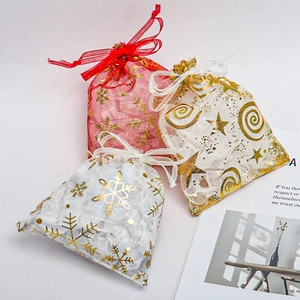 Close-up of red and white organza gift bags with gold snowflake and star foil prints