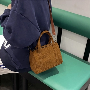 Brown corduroy Boston mini bag with crossbody strap shown being worn by a model
