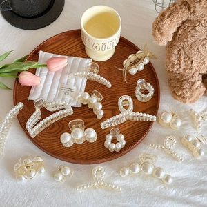 Elegant Korean style pearl hair claws set in various sizes on a rustic wooden tray