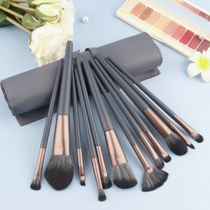 12-piece professional makeup brush set with grey PU leather roll bag on blue background