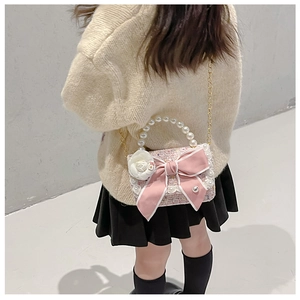 Detail of pink tweed girl's handbag featuring a large bow and pearl handle