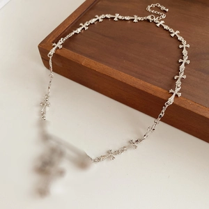 Close-up of silver safety pin and zircon cross link chain with gothic metallic texture