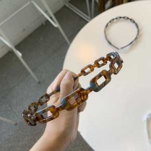 Detail of retro amber acetate chain headband showing tortoiseshell resin texture