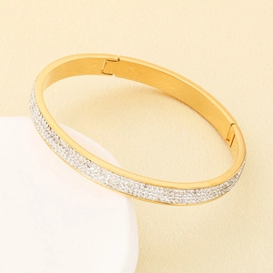 Bracelet jonc ovale doré avec strass scintillants sur un présentoir élégant