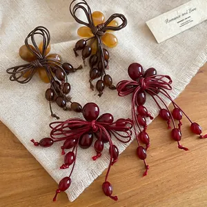 Vintage resin bow earrings with elegant long tassels in red and amber on linen surface