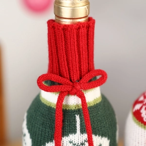 Knitted Christmas wine bottle cover with red bow and snowflake patterns on green fabric