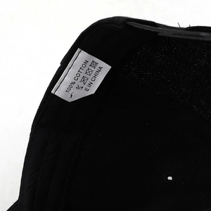 Detail of internal black baseball cap showing 100% cotton material and care label