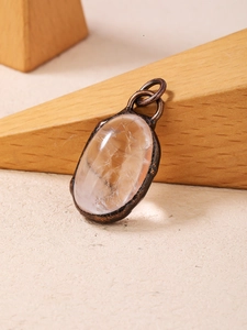 Detailed view of irregular clear crystal stone pendant set in a vintage bronze metal frame