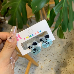 Close-up of cute light blue acrylic puppy dog stud earring on a decorative display card