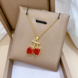 Detail of cherry pendant necklace with red heart crystals and gold chain on silk