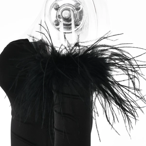 Close-up of elegant black dress sleeve featuring lush black feather cuffs on a model