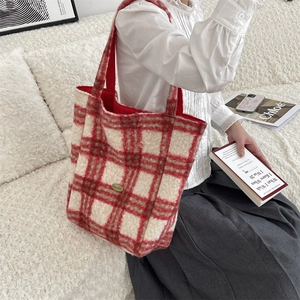 Close-up of red and white plaid fleece tote bag with golden logo and soft texture