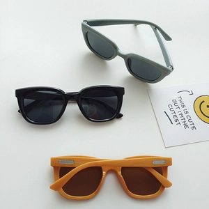 Detailed flat lay of children sunglasses in black, olive green, and bright yellow frames