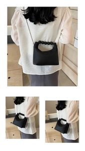 Detail showing high-quality black litchi pattern leather bag with pearl handle and chain