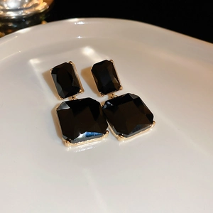 Detailed macro view of faceted rectangular black crystal drop earrings with gold claw settings