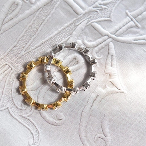 Close-up of slim gold and silver rings with cubic zirconia pavé on textured fabric
