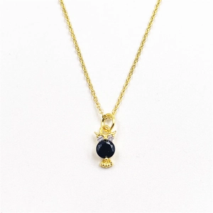 Detailed close-up of golden owl pendant with a black gem and micro-pave crystals