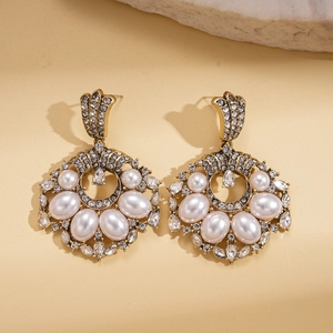 Detail of vintage gold pearl earrings with sparkling crystals on leather background