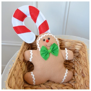 Detailed plush gingerbread man decoration with green bow and candy cane in a woven basket