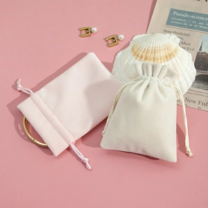 Close-up of pink and beige plush drawstring pouches for jewelry storage with seashell decor