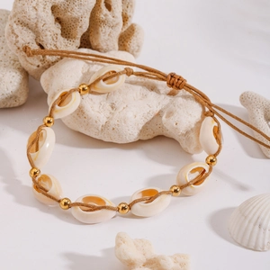 Detailed close-up of handmade cowrie shell beach anklet with gold beads on woven cord