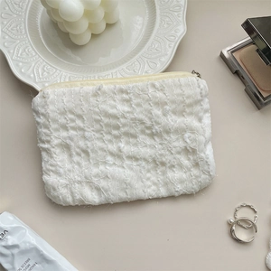Dettaglio macro della pochette in tessuto bianco strutturato con cerniera in metallo