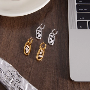 Orecchini a cerchio ovali in oro 18k e argento con zirconi su tavolo in legno