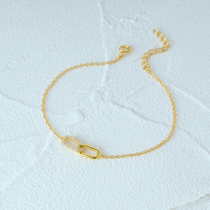 Detailed view of the double interlocking rings on the gold bracelet with zircon stones