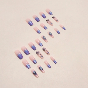 Detail of coffin-shaped press-on nails with purple gradient, skull and spider web designs