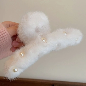 Vue détaillée d'une grande pince à cheveux en peluche blanche ornée de perles élégantes