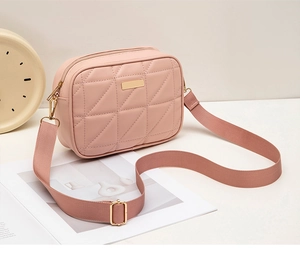 Detail of pink quilted crossbody bag showing faux leather texture and golden metal hardware