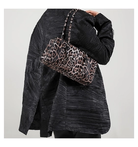 Detail of leopard print baguette bag on a model wearing a black textured winter coat
