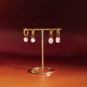 Detail view of gold hoop earrings with round and oval zircon charms on a display