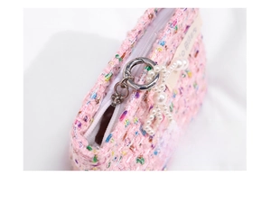 Detailed view of pink tweed fabric texture with smooth zipper and pearl strap