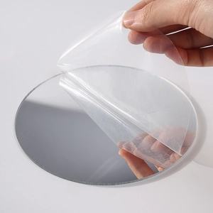 Hand peeling protection film from a round tassel woven wall mirror on white background
