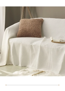 Detailed waffle texture of off-white cotton sofa cover featuring decorative tassels