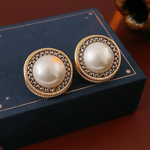 Gros plan sur boucle d'oreille perle vintage avec bordure dorée et maillon de chaîne argent