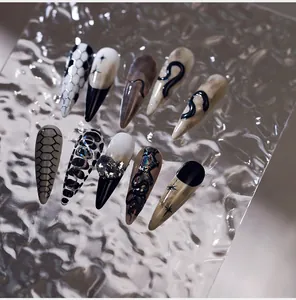 Detailed view of Gothic press-on nails featuring 3D snake relief and black plaid patterns