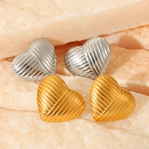 Macro shot of gold and silver heart-shaped stud earrings with vertical striped texture