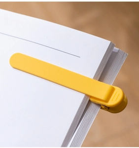 Close-up of yellow silicone auto-follow bookmark clipped on a notebook page edge