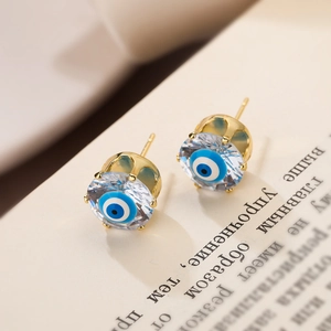 Detailed view of evil eye stud earring with blue crystal and gold-plated copper base