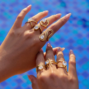 Close-up of gold titanium rings with zircon crystals on hand by blue mosaic water