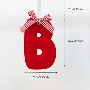 Red felt Christmas letter B ornament with a plaid bow and gold bell hanging on white background
