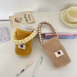 Vista detallada de las bolsas de peluche para botellas en amarillo y beige con asas a cuadros