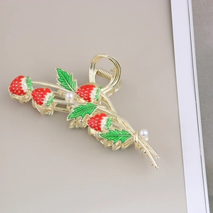 Détail de la pince à cheveux en métal doré avec motifs fraises rouges et petites perles