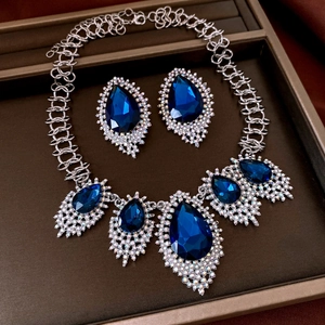 Detail of silver chain necklace and blue teardrop pendant with sparkling crystals