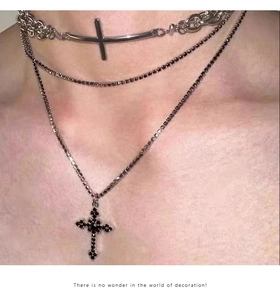 Close-up of layered punk cross necklaces with silver bars and black crystal pendant