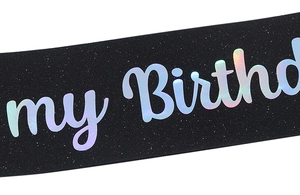 Close-up of glittery black fabric birthday sash with holographic silver lettering