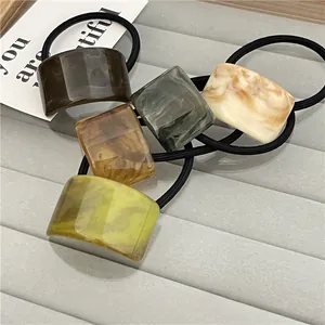 Detailed shot of amber marble resin hair ties on a grey velvet jewelry display tray