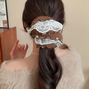 Detailed view of elegant brown knit scrunchie with white lace trim on a ponytail